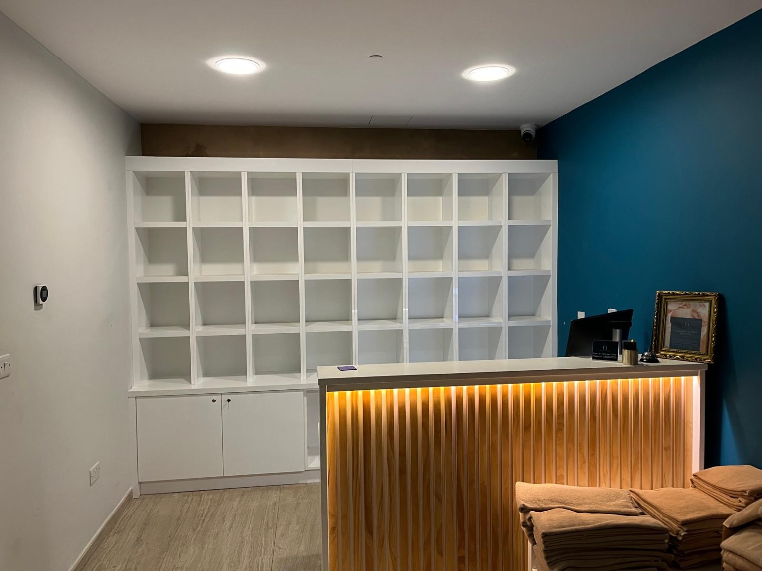 Bespoke commercial reception unit with illuminated timber-slat front and fitted display shelving.