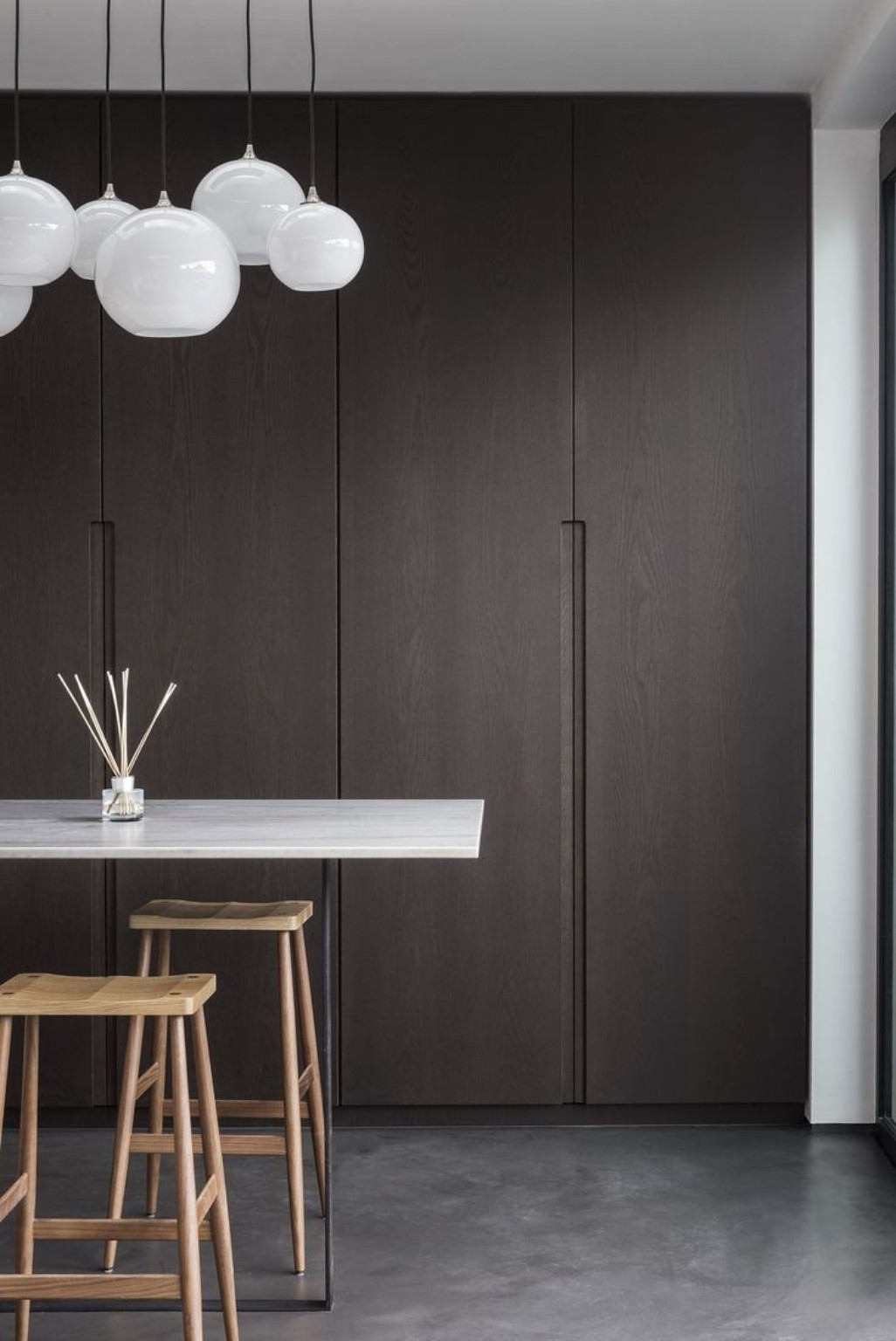 Dark wood floor-to-ceiling fitted kitchen cabinetry with concealed storage.