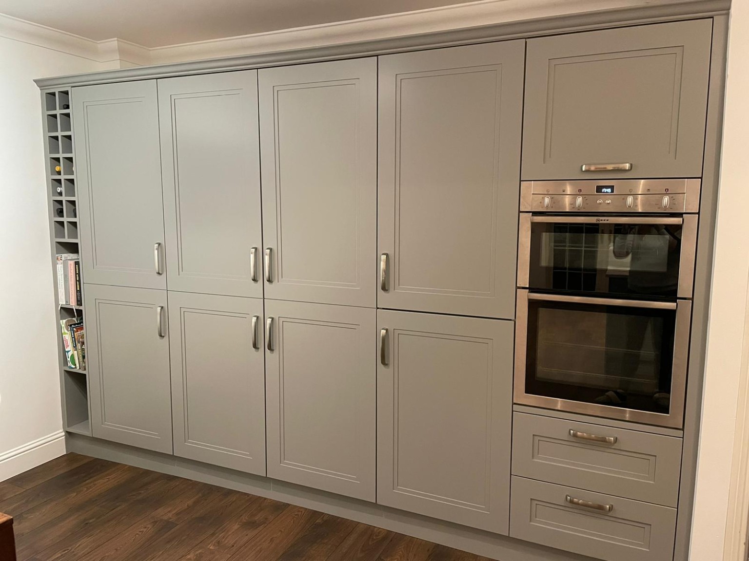 Floor-to-ceiling grey Shaker kitchen cabinetry with integrated double ovens and wine storage.