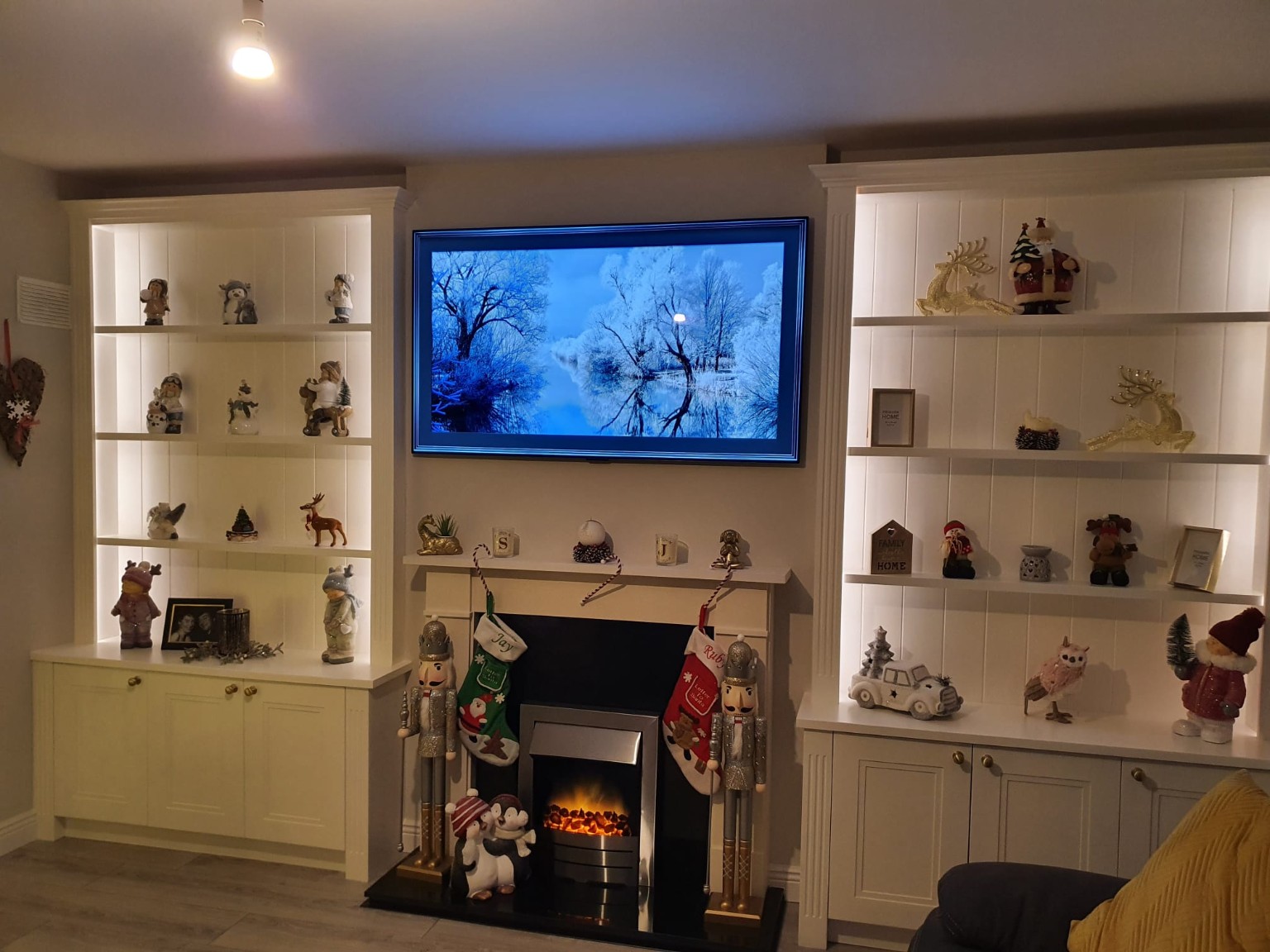 White built-in fireplace cabinetry with illuminated display shelving and concealed storage.