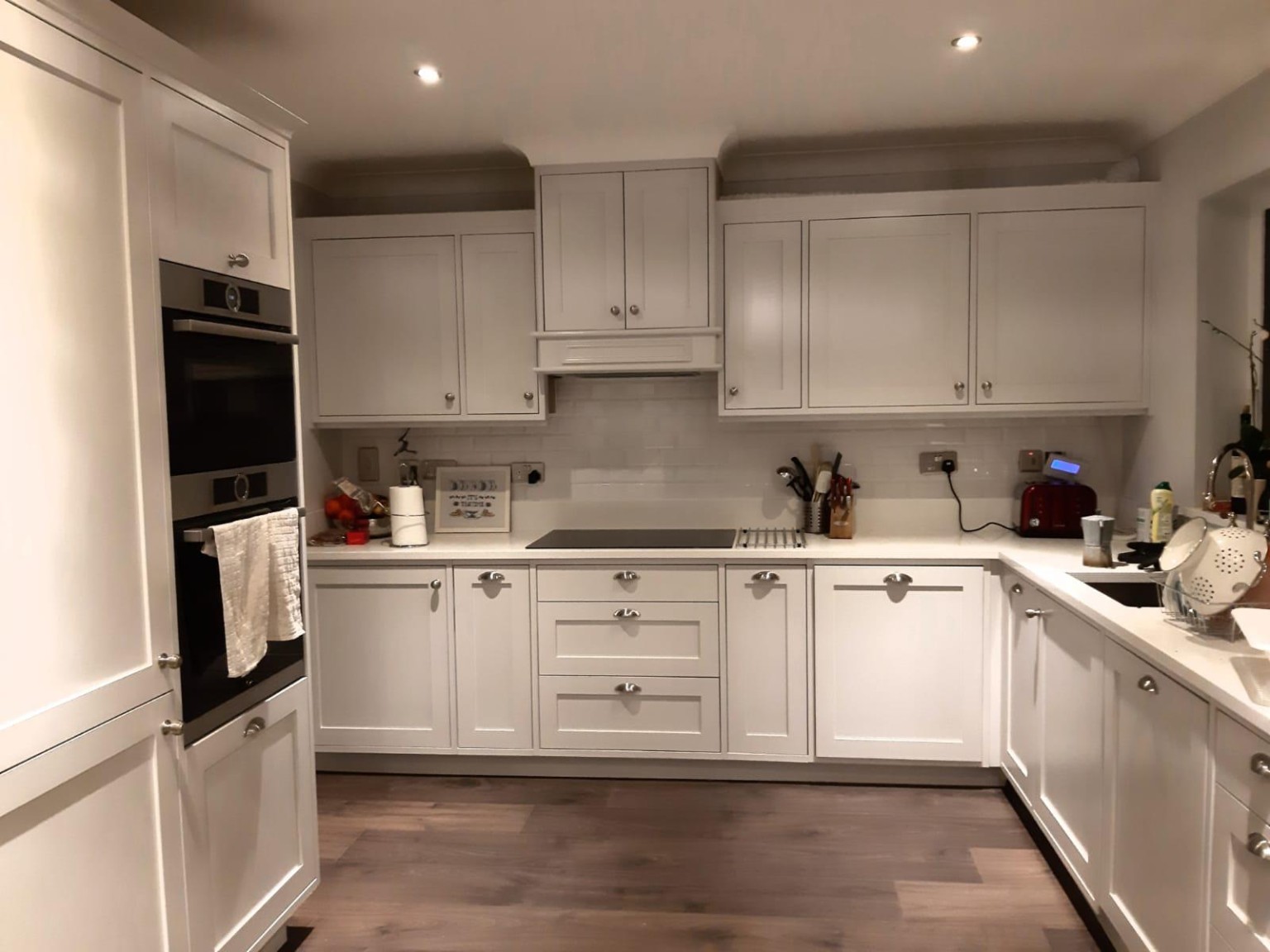 Bespoke white Shaker-style U-shaped kitchen with integrated appliances and cabinetry.